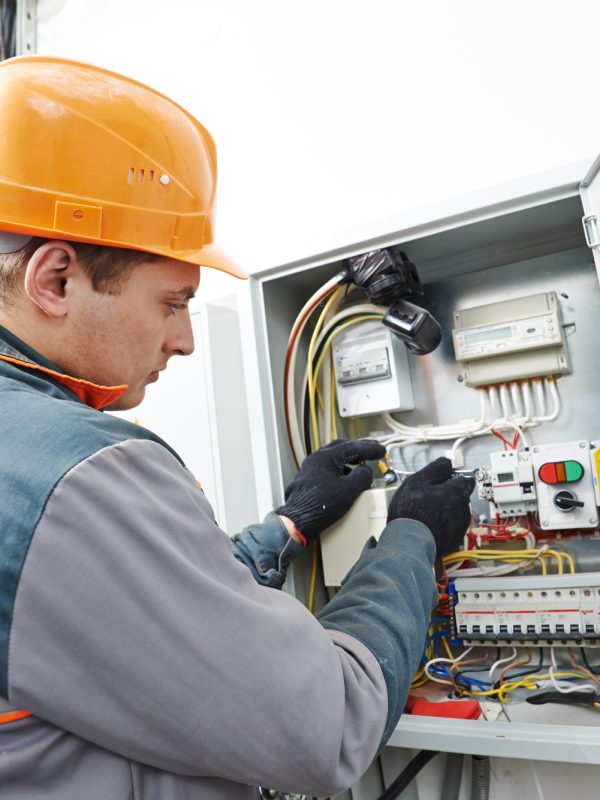 electrician engineer worker Young adult electrician builder engineer screwing equipment in fuse box