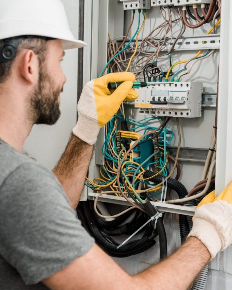 side-view-of-electrician-repairing-electrical-box-and-using-screwdriver-in-corridor-e1616025446714 side-view-of-electrician-repairing-electrical-box-and-using-screwdriver-in-corridor-e1616025446714